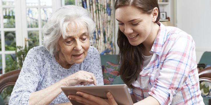 Jugendliche erklärt Seniorin die Funktionsweise eines Tablets