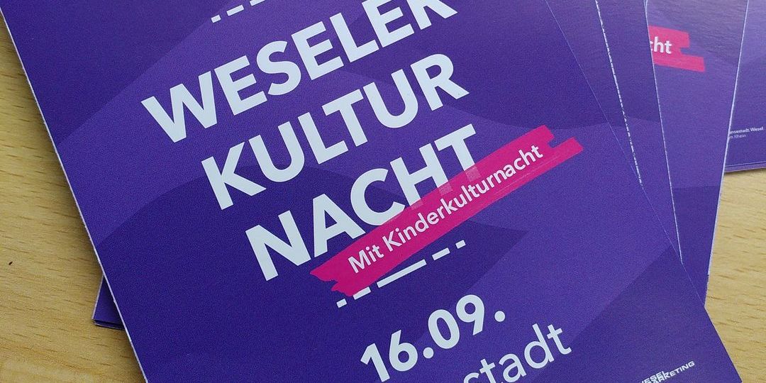 Mehrere Flyer der Weseler Kulturnacht liegen ausgebreitet auf einer Theke 