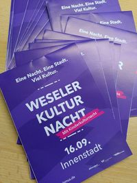 Mehrere Flyer der Weseler Kulturnacht liegen ausgebreitet auf einer Theke 